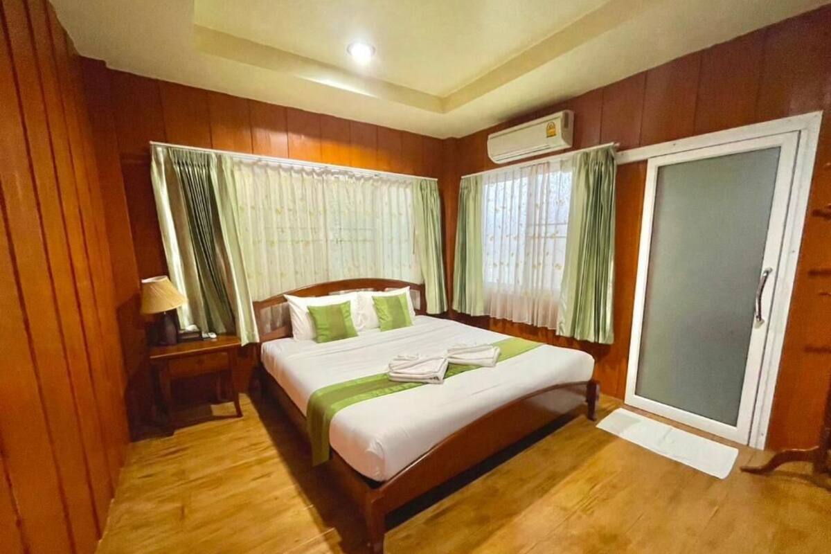 A wooden-paneled bedroom with a bed, a nightstand, an air conditioning unit, and a sliding glass door.