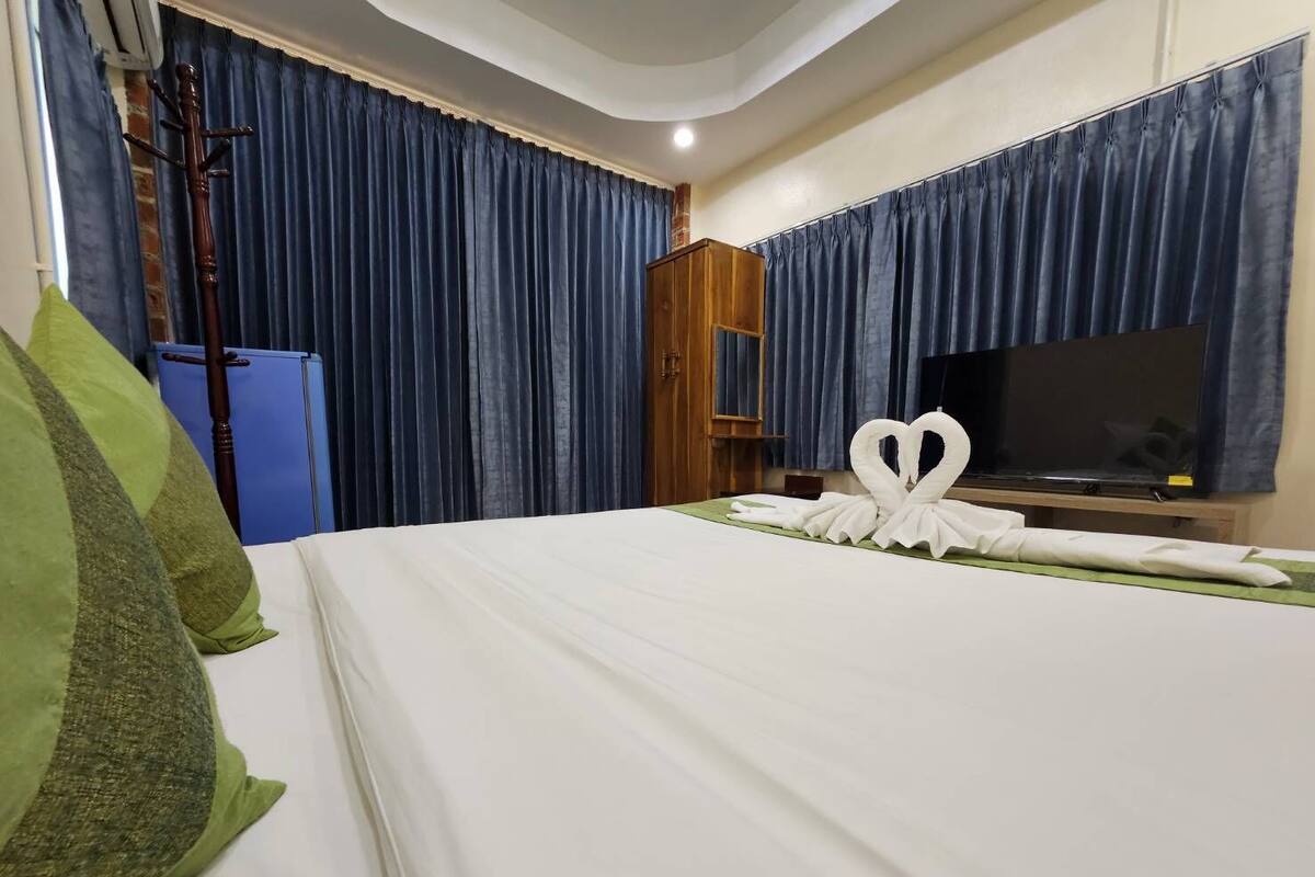 A hotel room with a bed, a television, and a coat rack.