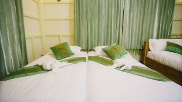 A hotel room with two beds, each with white bedding and green accents, and a wooden headboard.