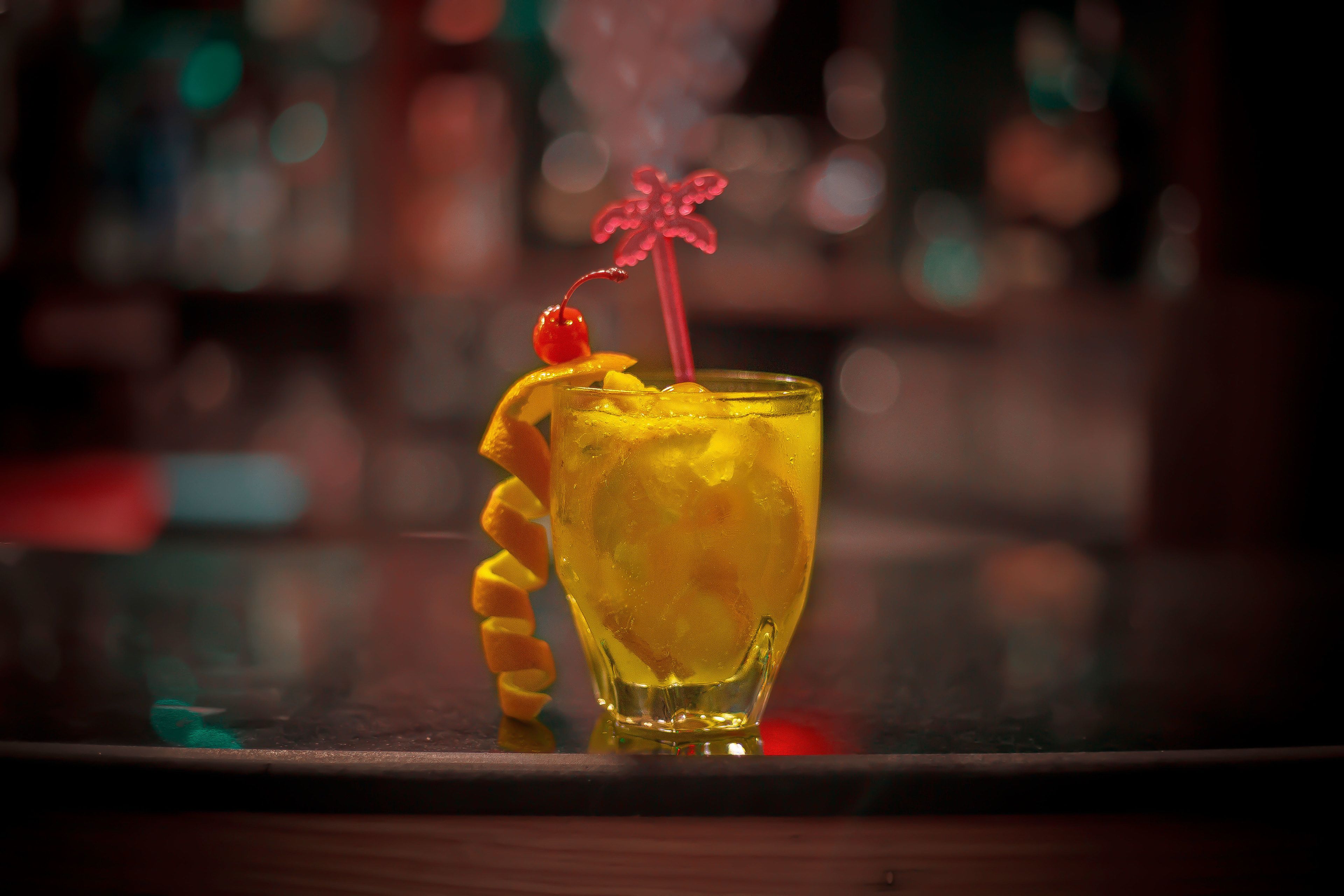 Un cocktail con una ciliegina e una cannuccia decorativa in un bicchiere.