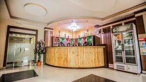Ein Empfangsbereich mit Holztresen, einem Coca-Cola-Kühlschrank und einem Glastür-Eingang.