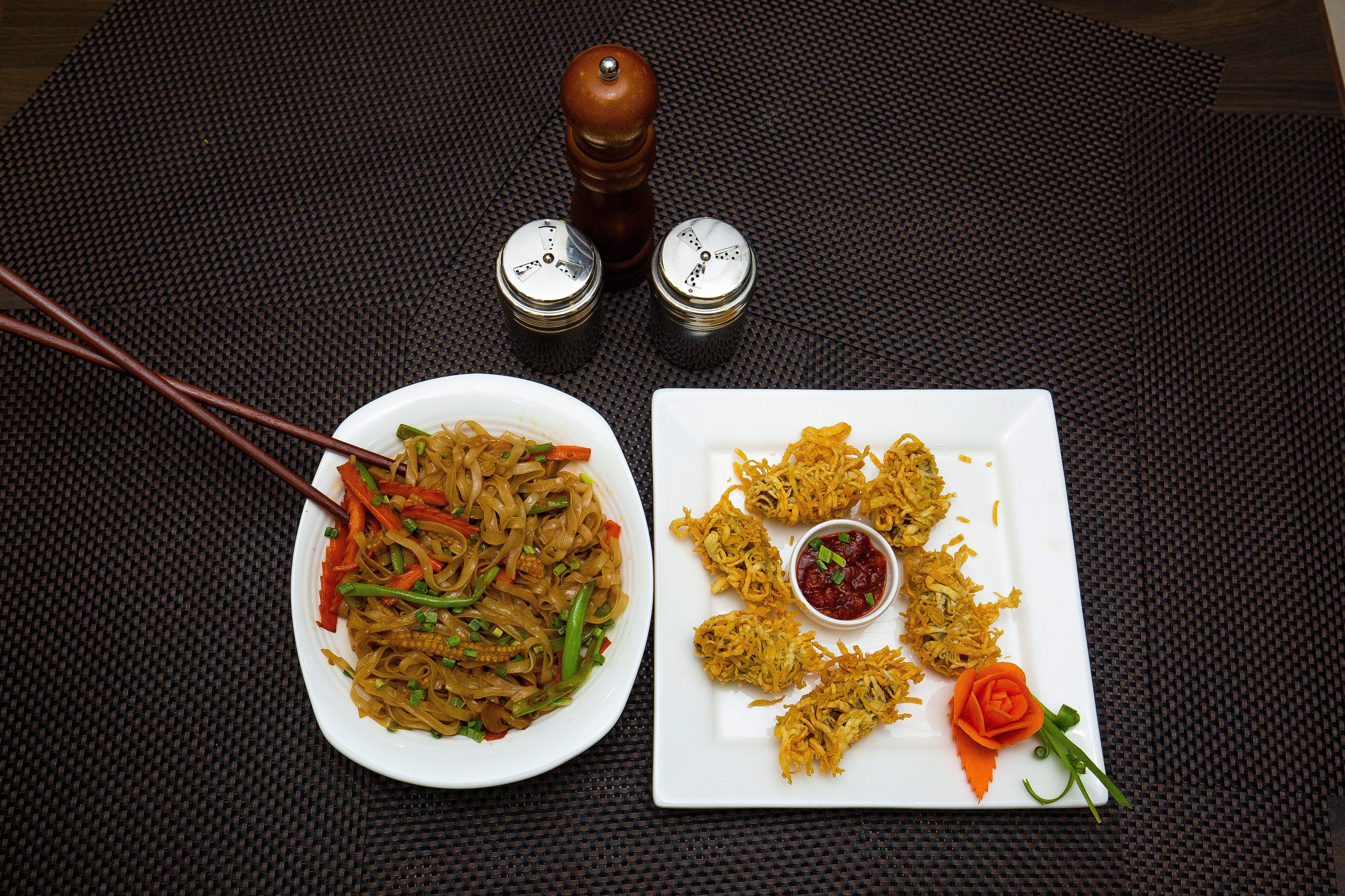 Una mesa con dos platos, palillos y saleros y pimenteros.