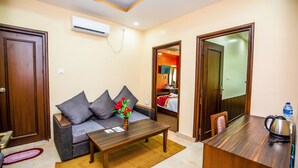 Ein Hotelzimmer mit Sofa, Couchtisch, Schreibtisch aus Holz und einer Klimaanlage.