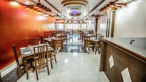 Ein Restaurant mit einem zentralen Essbereich, mehreren Tischen und Stühlen.