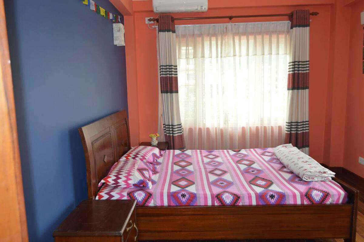 A bedroom with a wooden bed, a nightstand, and a window with curtains.