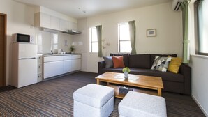Un espacio habitable compacto con kitchenette, un sofá, una mesa de centro y un pequeño rincón de descanso.