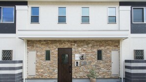 Una casa adosada moderna con fachada de piedra, una puerta central y un pequeño jardín.