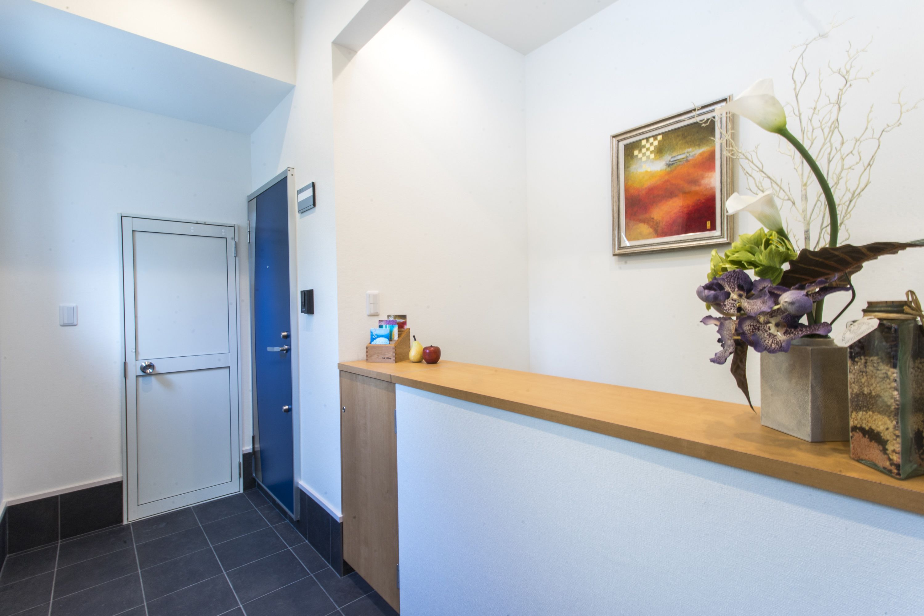 Ett receptionsområde med en bardisk i trä, en dörr och en inramad tavla på väggen.