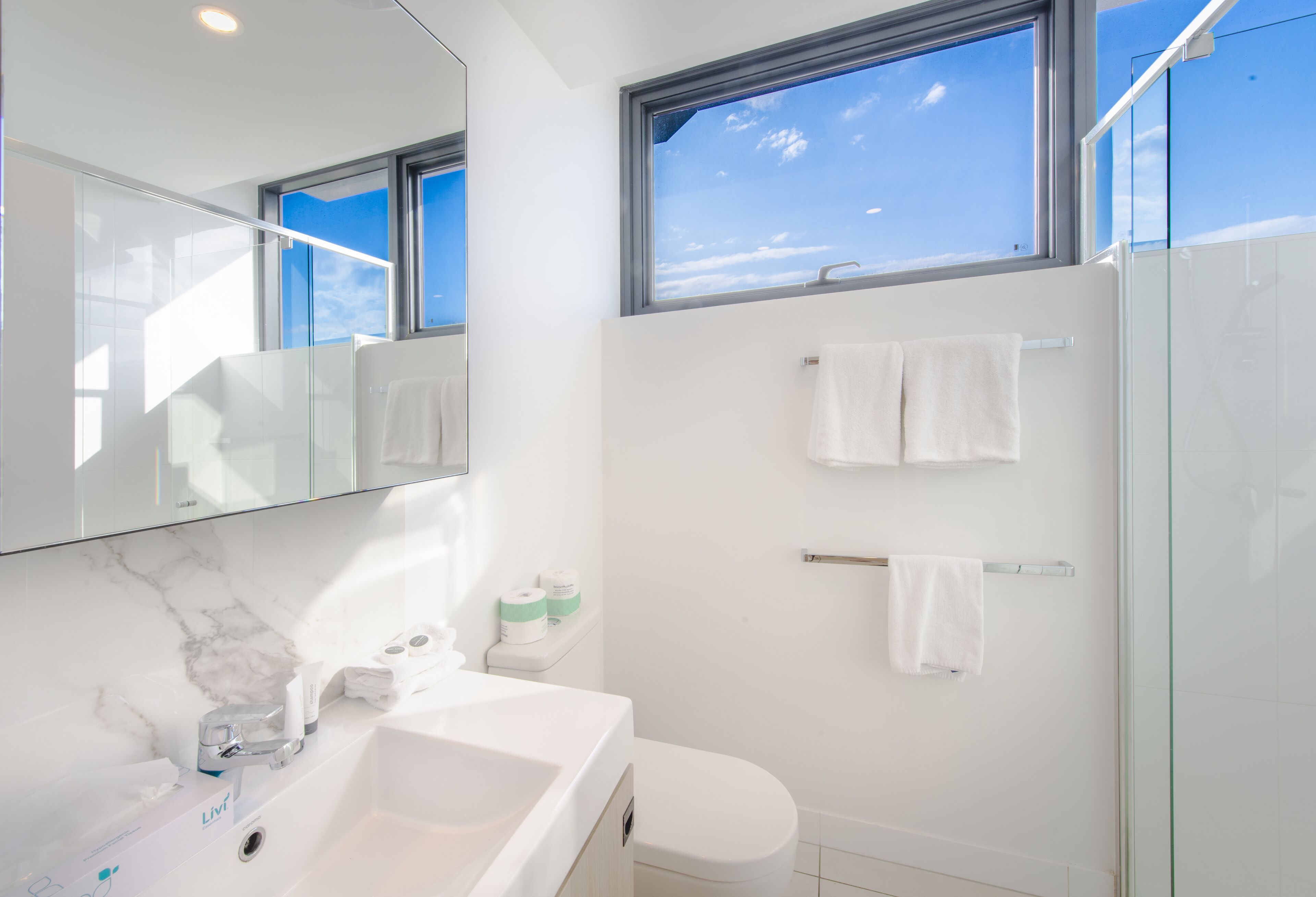 Une salle de bain moderne avec un grand miroir, une baignoire, des toilettes et une douche à parois de verre.