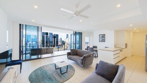 Een moderne woonkamer met uitzicht op de stad, een plafondventilator en een keukenhoek.