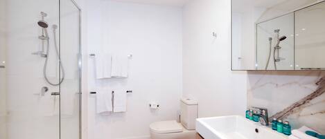 Une salle de bain moderne avec une douche à parois de verre, des toilettes et un lavabo équipé de produits de toilette.