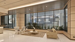Een moderne lobby met een grote glazen wand, een receptiebalie en een zithoek.