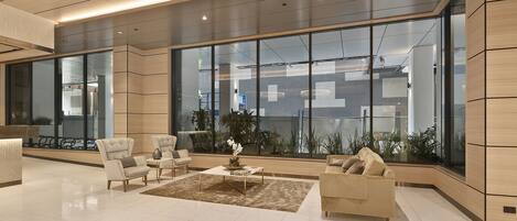 A modern lobby with a large glass wall, a reception desk, and seating area.
