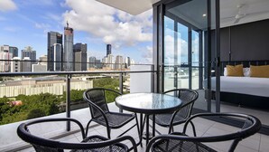 Een moderne hotelkamer met balkon, glazen wand en uitzicht over de stad.