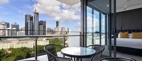 Una habitación de hotel moderna con balcón, pared de vidrio y vista a la ciudad.