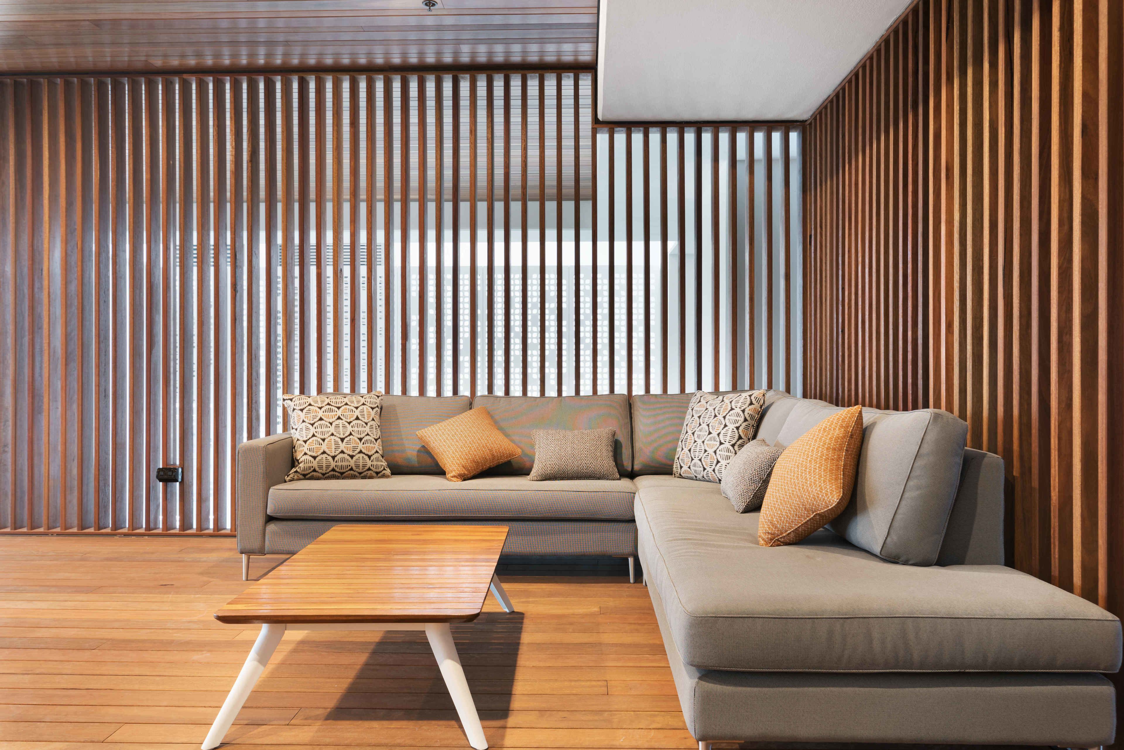 A modern living room with a sectional sofa, a wooden coffee table, and vertical wooden slats on the walls.