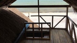 Vista al mar desde una habitación en el ático, con suelo de madera y techo de paja.