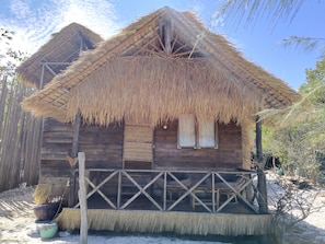 A wooden cabin with a thatched roof and a simple porch.