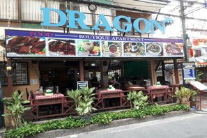 A restaurant named 'Dragon' with outdoor seating and a signboard advertising food, boutique apartments, and beverages. - Dragon Serviced Apartment (Pattaya)