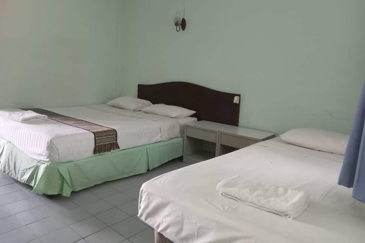 A room with two beds, each with a headboard, a bedside table, and a wall-mounted light fixture.