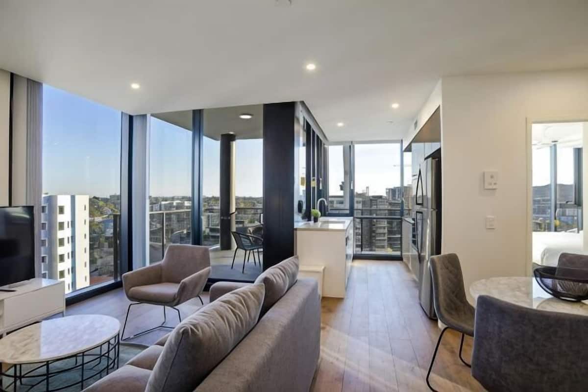 A modern living room with a sofa, chairs, a small table, and a TV.
