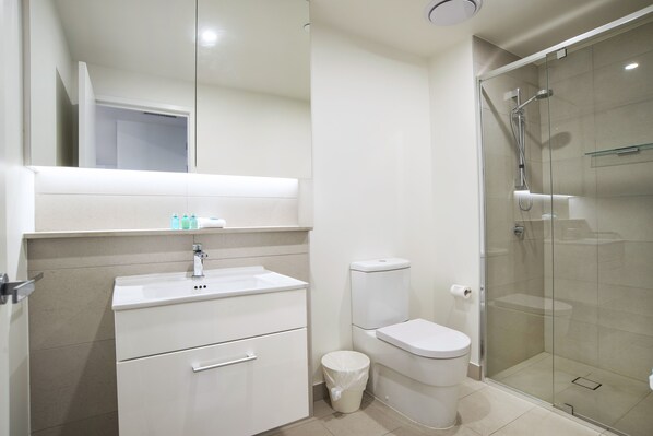 A modern bathroom with a white sink, toilet, and glass shower enclosure.
