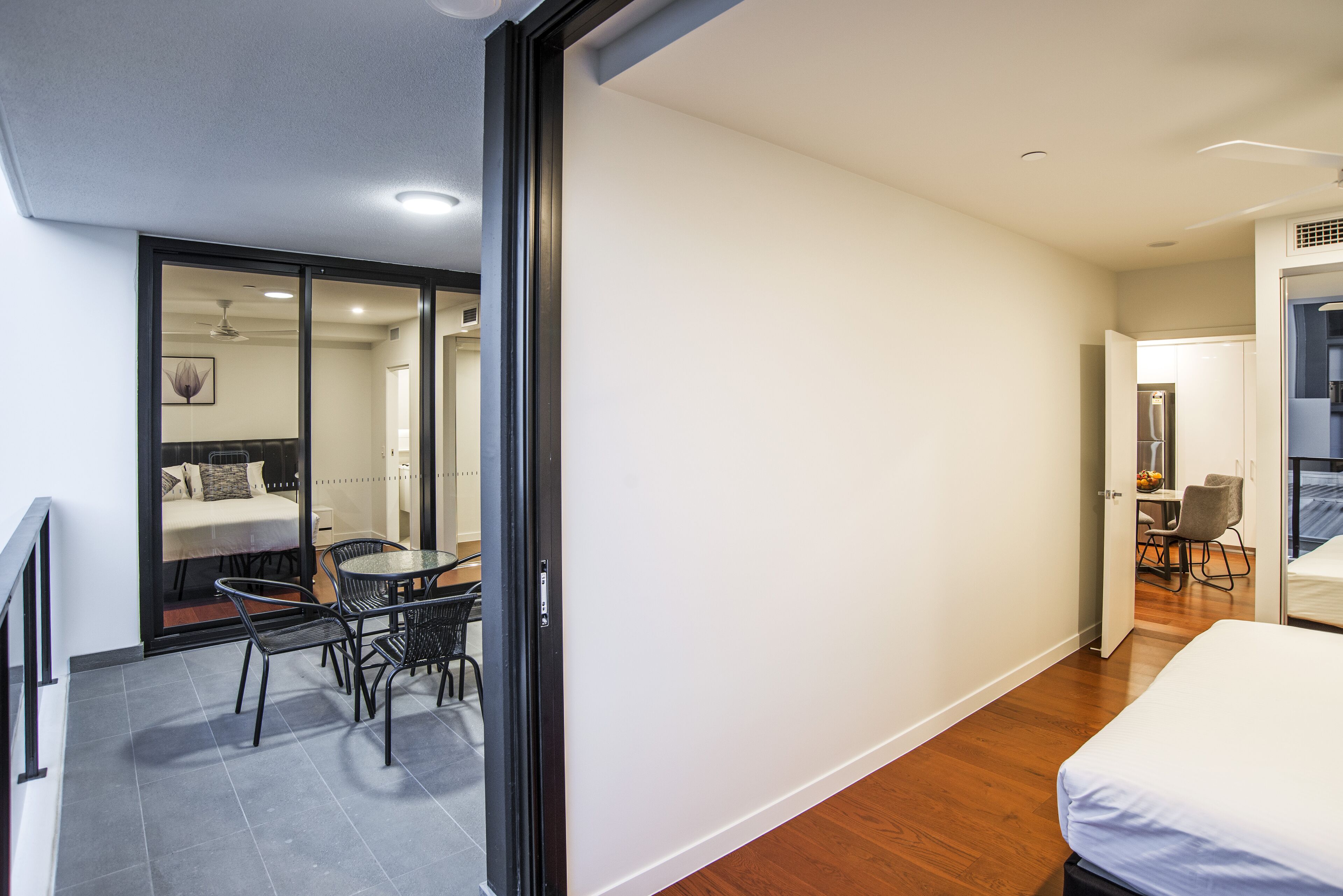 Une chambre d’hôtel moderne dotée d’un balcon, d’un coin repas et d’une chambre à coucher séparée.