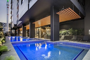 Una piscina interna moderna con piastrelle blu, circondata da poltrone relax e un'area salotto coperta.