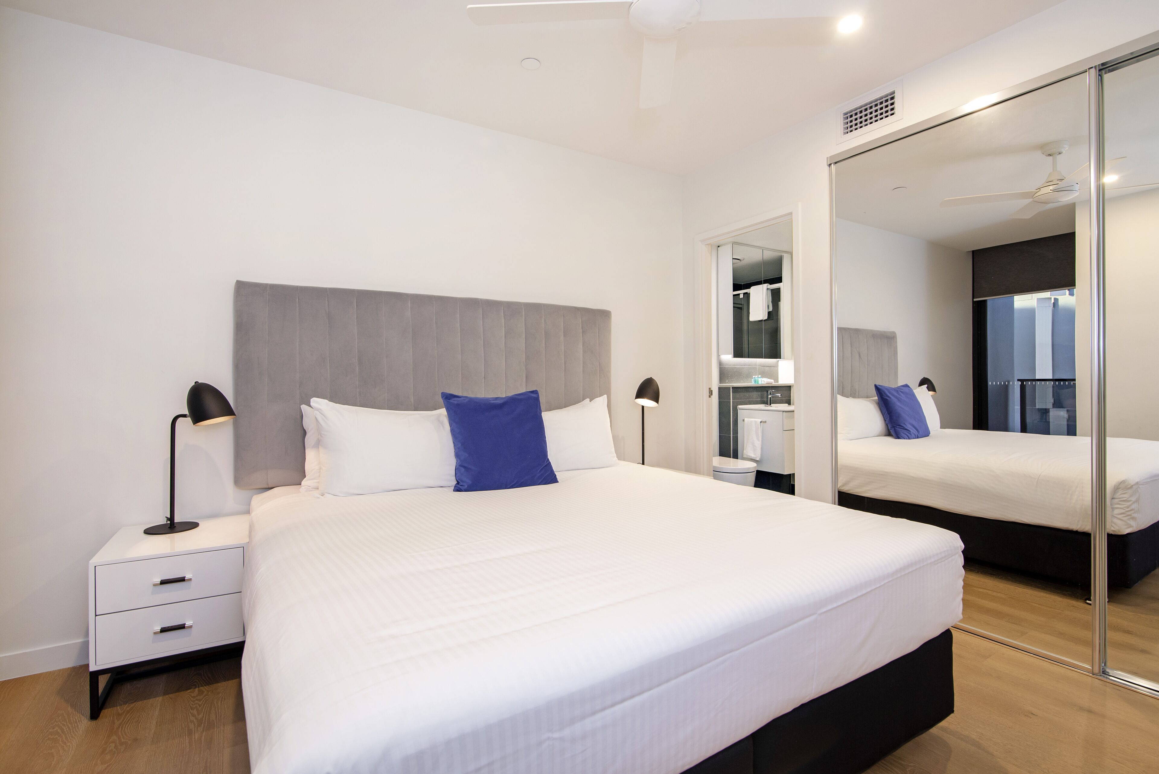 Une chambre d’hôtel moderne avec un grand lit, des tables de chevet et un miroir.