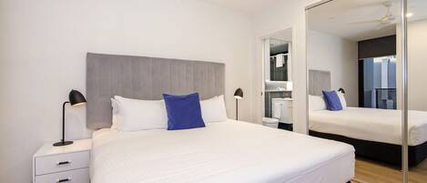 Una habitación de hotel moderna con una cama grande, mesitas de noche y un espejo.