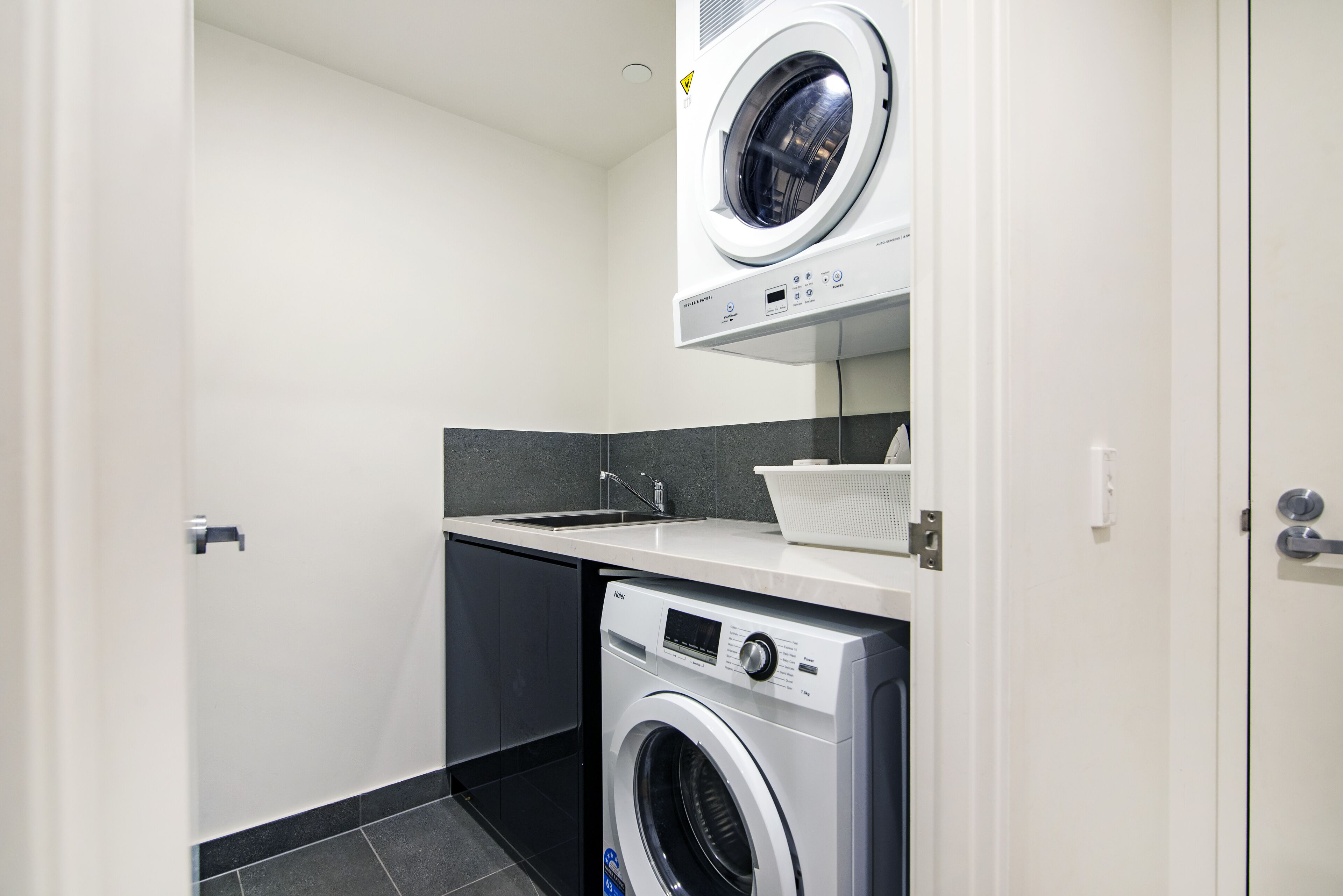 A compact laundry room with a front-loading washing machine and a top-loading dryer.