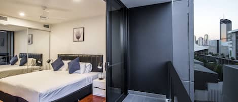 A modern hotel room with a large bed, bedside tables, a mirror, and a balcony with a city view.