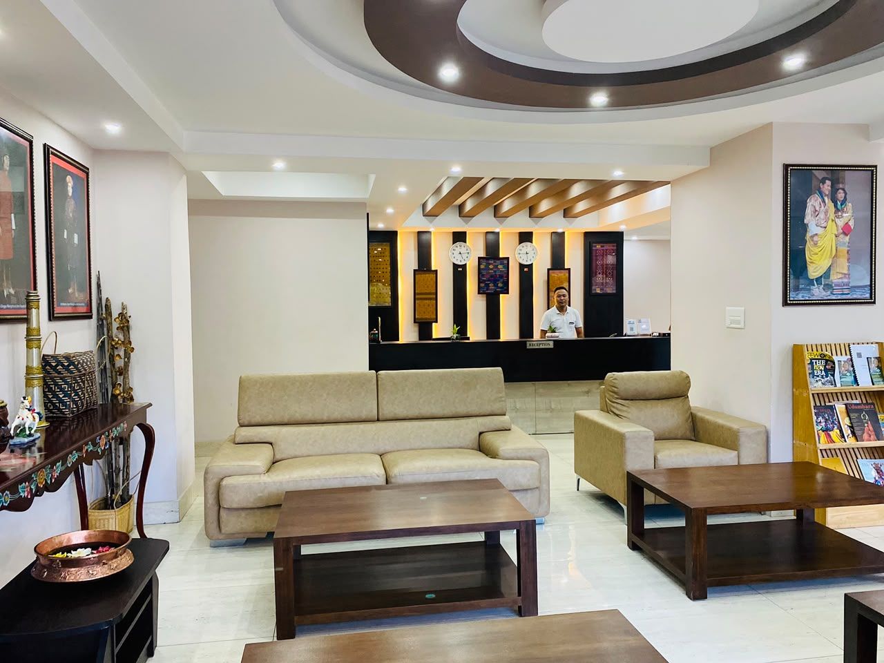 Um saguão de hotel com balcão de recepção, sofás e mesa de centro.