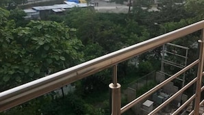 Un balcón con barandilla de metal que da a una zona residencial con edificios de varios pisos y vegetación.