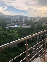 A balcony with a metal railing overlooking a residential area with multi-story buildings and greenery.