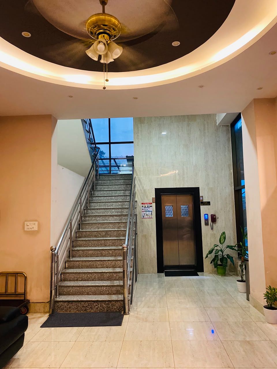 Um saguão de hotel com uma escada, um balcão de recepção e uma porta com a inscrição 'Lobby'.