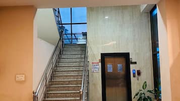 Um saguão de hotel com uma escada, um balcão de recepção e uma porta com a inscrição 'Lobby'.
