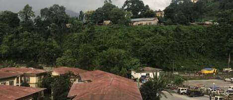 A residential area with buildings, a winding road, and a hilly backdrop.