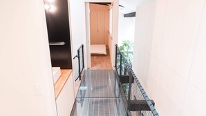 A modern interior with a tiled floor, a staircase, and a view of a room with a bed and a window. - Yaoya Kyoto Kyomizu Gojo (Kyoto)