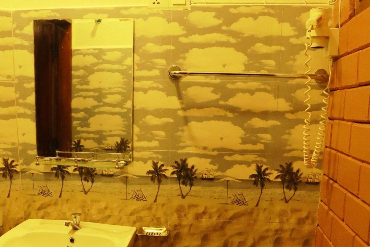 A bathroom with a stone wall, a white sink, and a toilet.