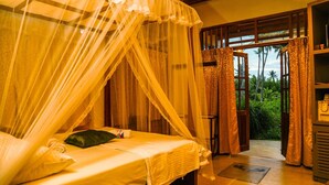 A room with a bed under a canopy, a view of greenery outside, and a door leading to another area. - Milkyway Holiday Resort (Unawatuna)