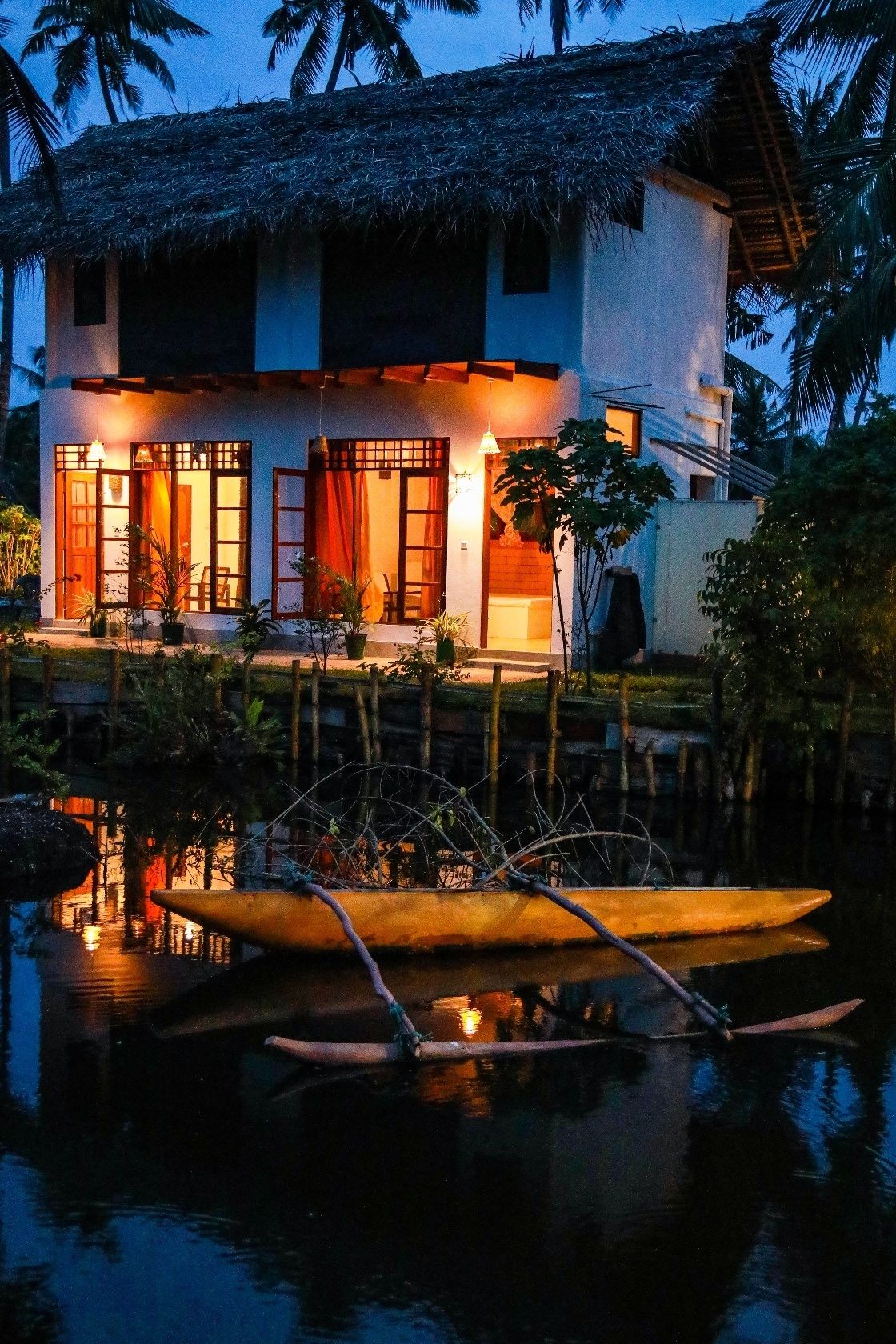 Una casa a due piani con tetto di paglia, immersa in un'acqua calma.
