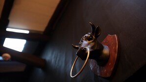 A brass door knocker with a bull's head design mounted on a dark wall. - Zhengxing Yanping Homestay (Tainan)
