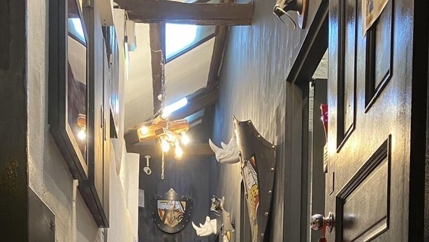 A narrow hallway with a stone floor, a welcome mat with a cat design, and various decorative items on the walls. - Zhengxing Yanping Homestay (Tainan)