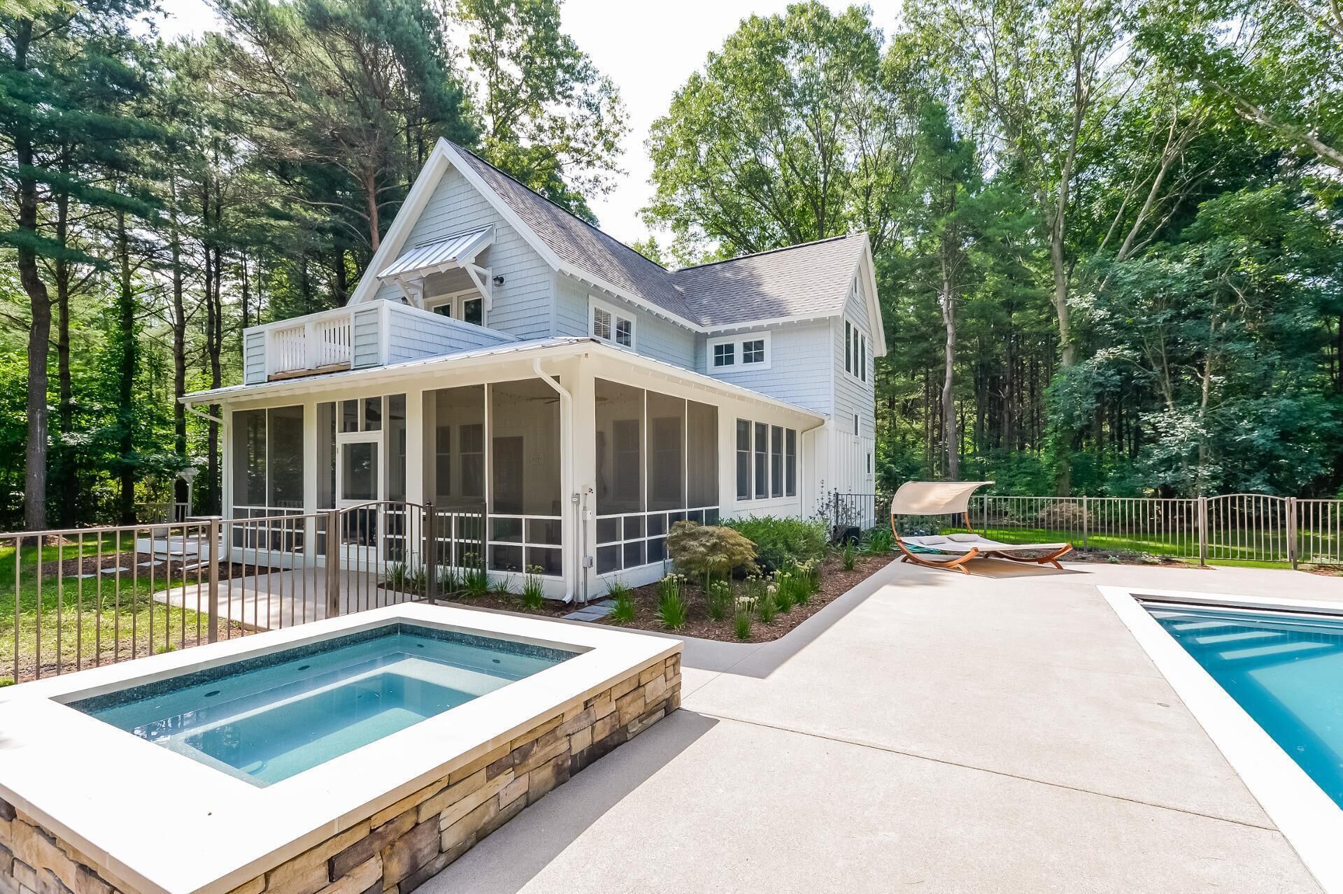 Une maison à deux étages avec un porche couvert, une piscine et une cour clôturée.