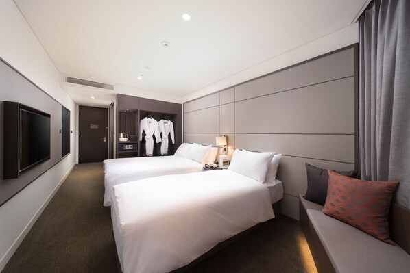 Una habitación de hotel con dos camas, televisión, zona de estar y vestidor.