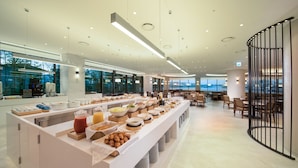 Un espace moderne dédié au petit-déjeuner dans l’hôtel, avec un buffet proposant une variété de plats et de boissons.