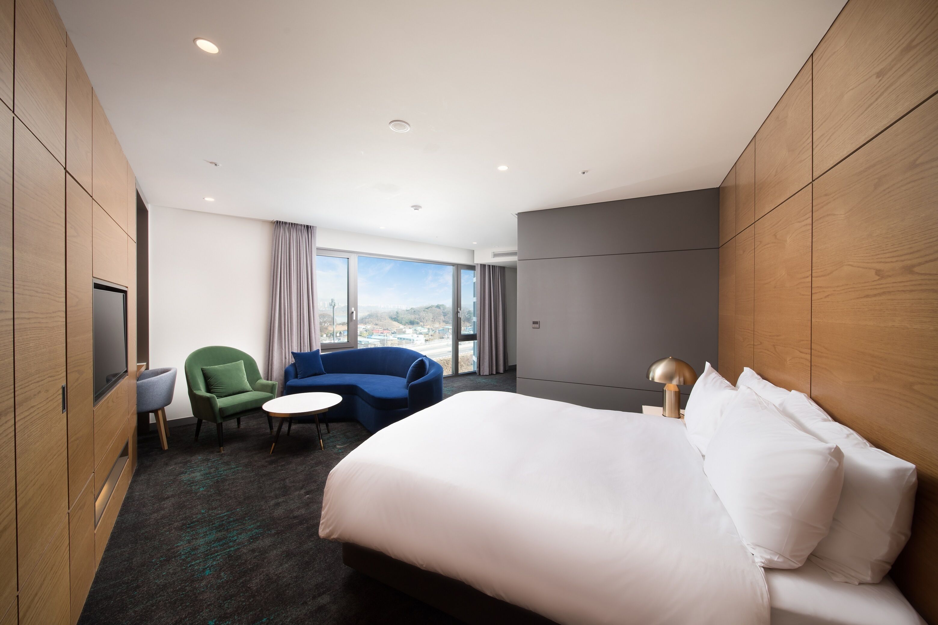 A hotel room with a large bed, a sofa, a small table, and a TV.