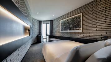 Una habitación de hotel moderna con pared de ladrillo, una cama grande, un escritorio y una ventana con cortinas.