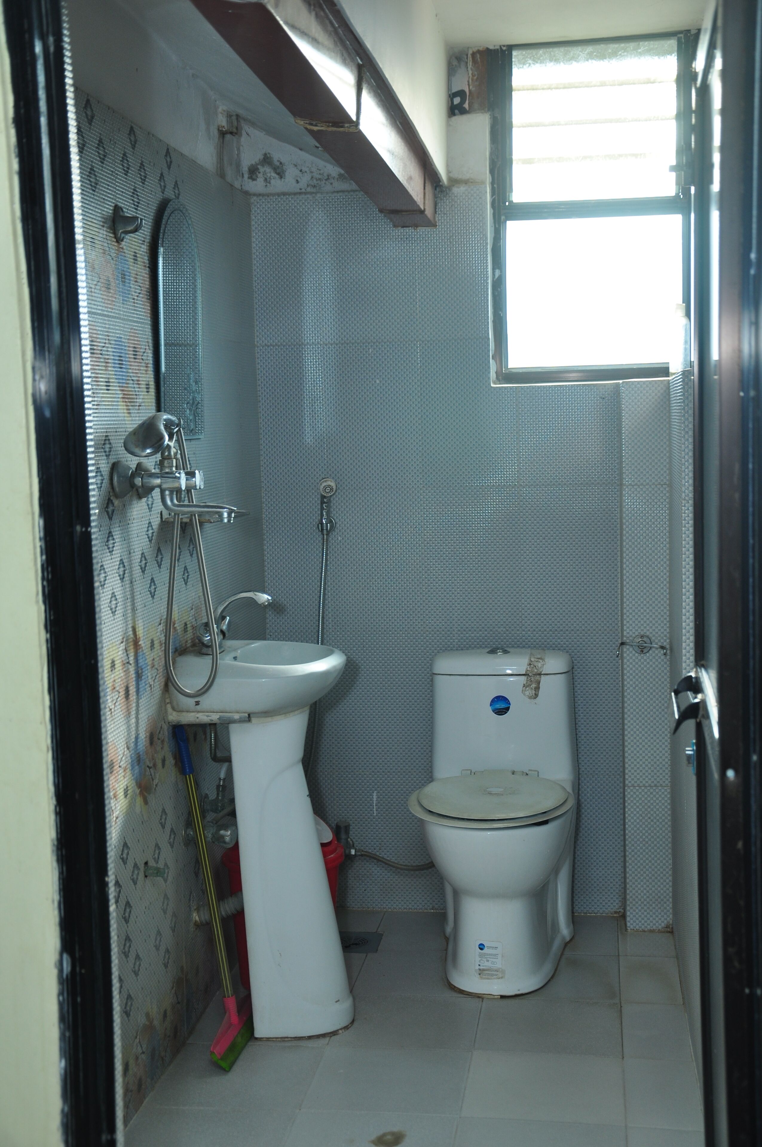 A small bathroom with a toilet, sink, and shower.